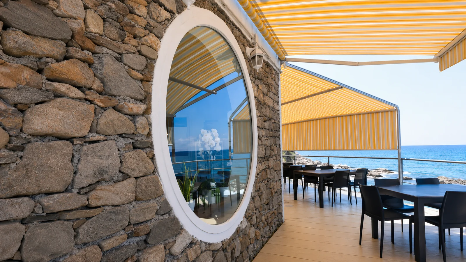 Terrazza esterna OBLO' con tende gialle e parete in pietra