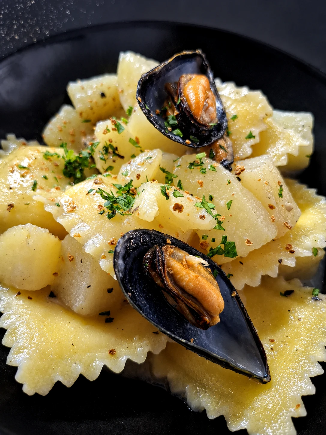 Ravioli con cozze serviti in piatto nero al ristorante OBLO'