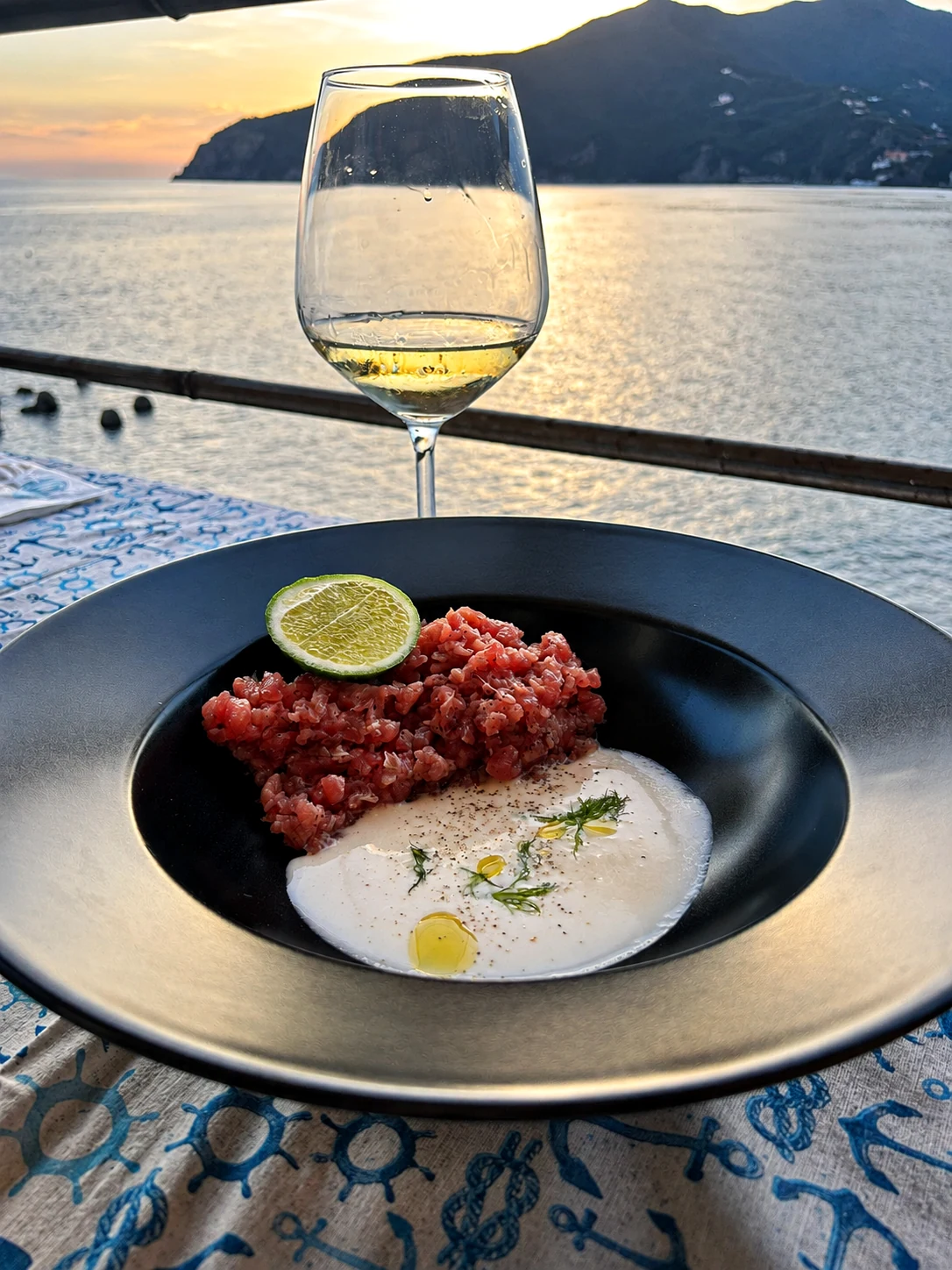 Tartare di tonno con calice di vino davanti al mare